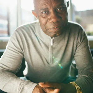 Older African american man looking into the camera with light shining in through a window over his right shoulder