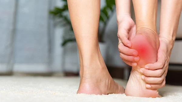 A photograph depicting a person holding their painful right foot. The pain is emanating from the heel. Is this heel pain a sign of cancer?